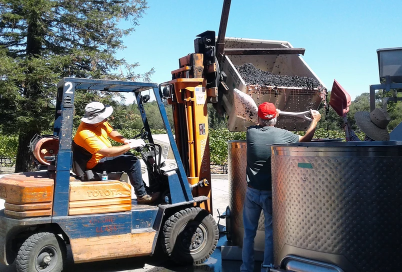 A man in an orange shirt is on the forklift.