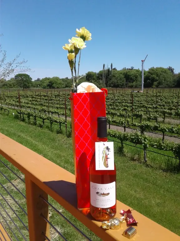 A bottle of wine and a vase on the railing.