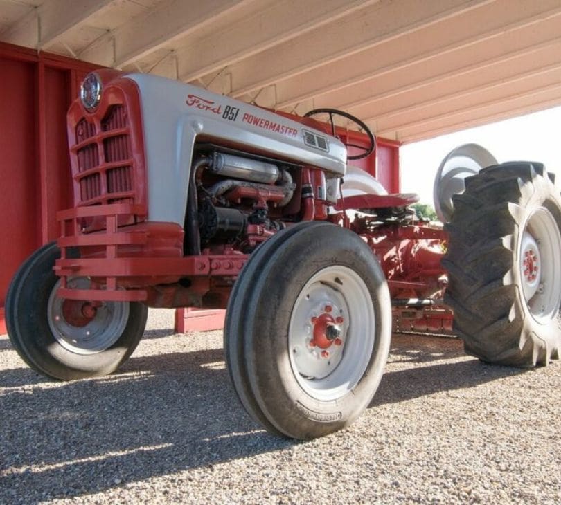 A tractor parked under a covered area with a tarp.