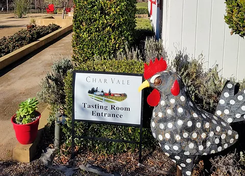 A chicken statue in front of a sign.